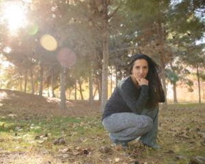 Photo of Paula Pant crouching down in the middle of woods